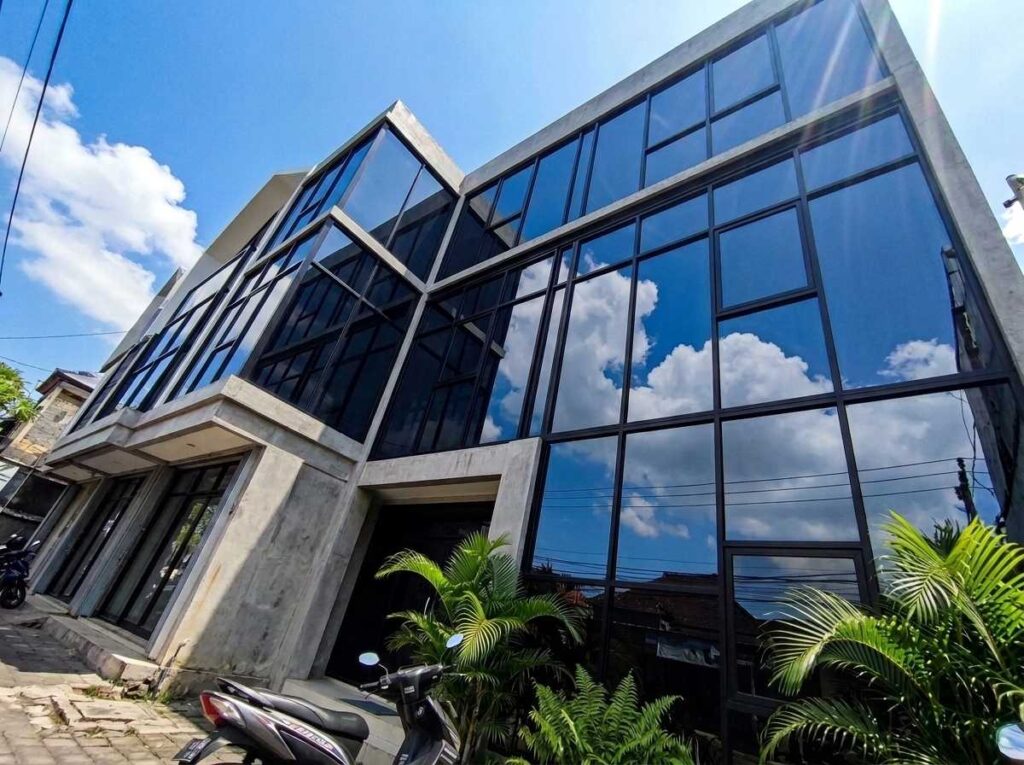 Aplikasi kaca film gedung komersial pada fasad bangunan perkantoran di Bali untuk meredam panas.